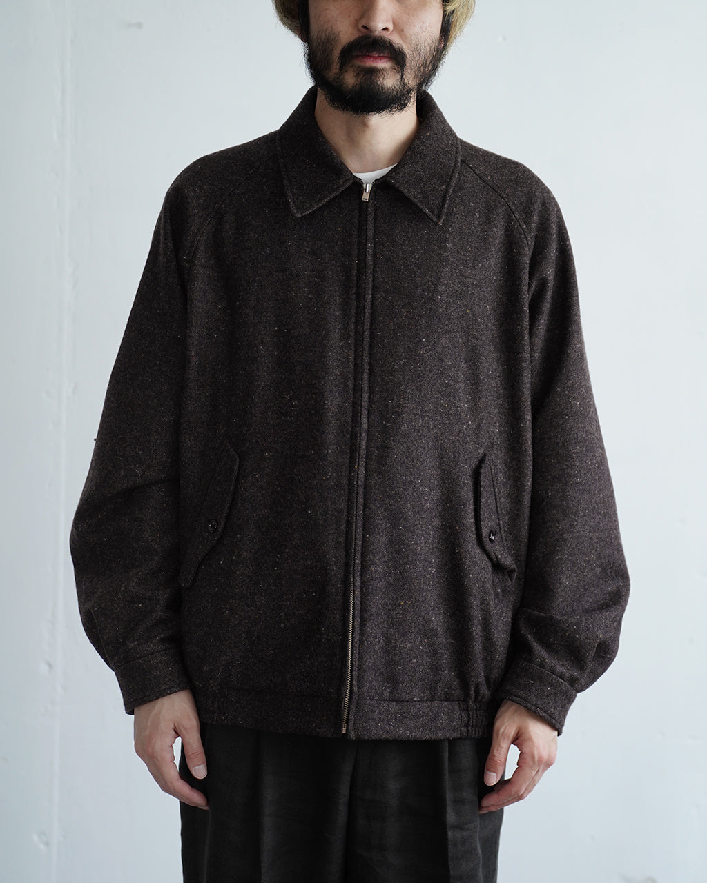 ダークセピアの Harrington ジャケットが前開きジッパーとスタンドカラーで着用できる2WAY仕様。前面ポケットは斜めフラップで実用的、襟元はボタン留めで雰囲気を変えられるデザインです。