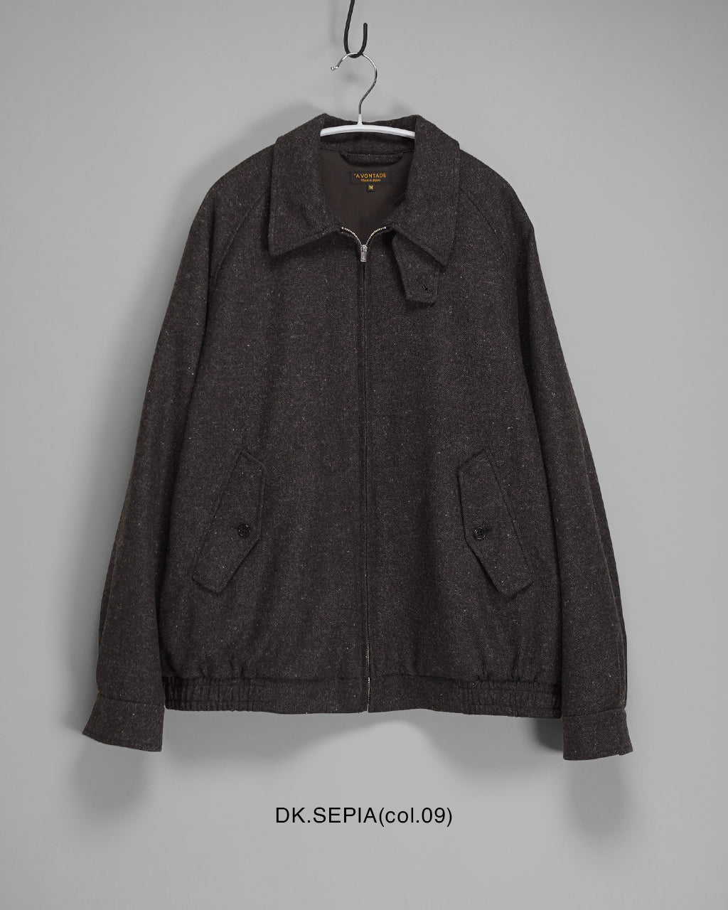 濃いセピア色の Harrington ジャケットを正面から着用イメージ。ジップ仕様とスタンドカラーが際立ち、前身頃のポケットや裾のエラスティックが特徴的に見える。