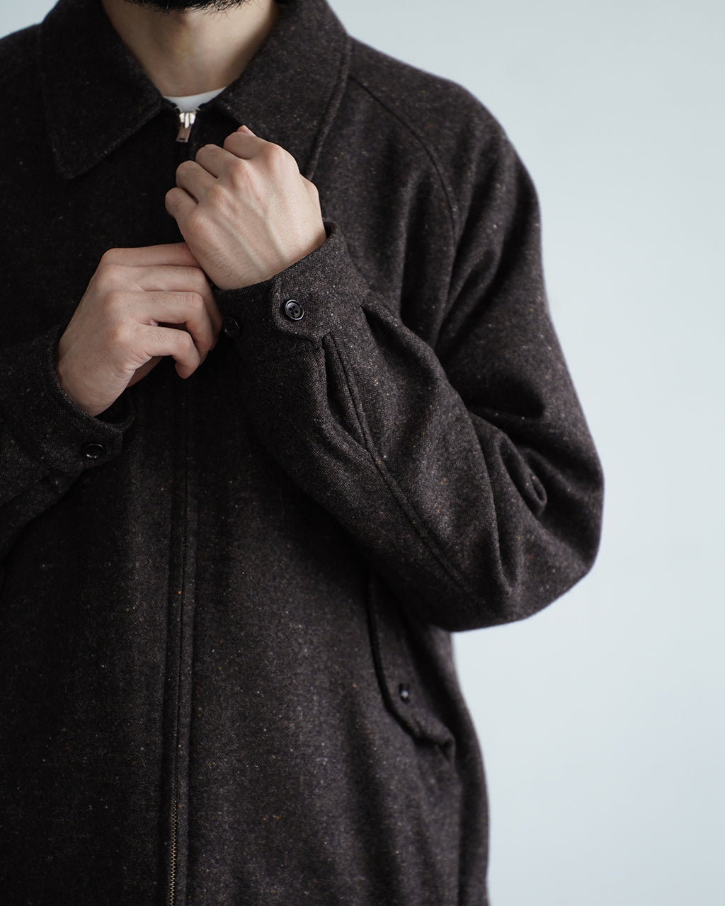 ダークセピア系の Harrington ジャケットを前身頃のアップで撮影。表情のあるウール混素材と立ち上がる襟、前立てのファスナー周りが見える寄りのショットです。