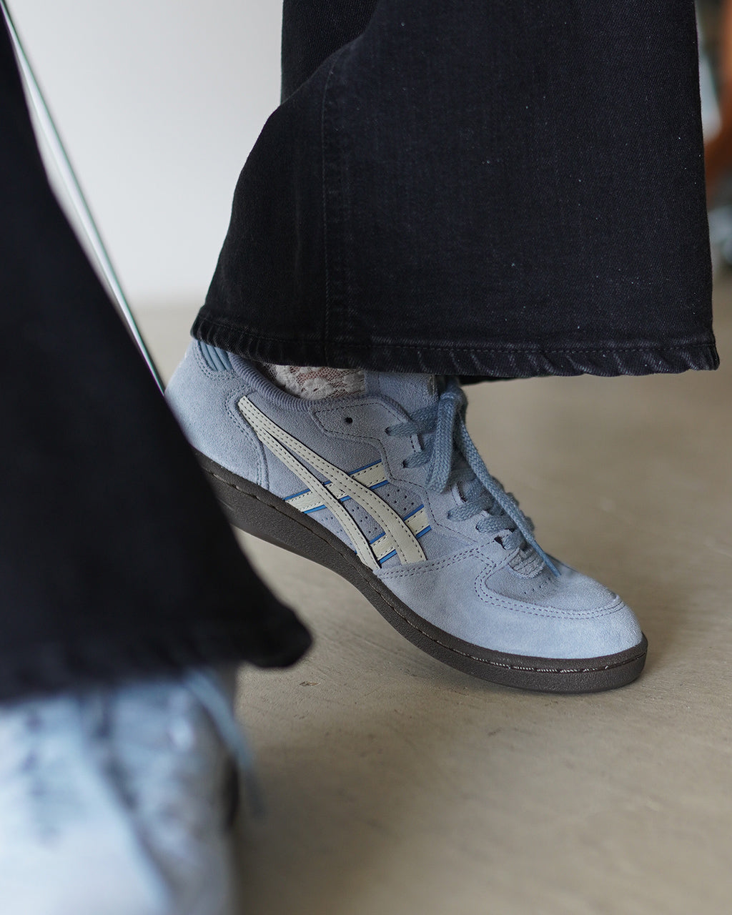 ASICS SKYHAND OGの淡いブルーのスニーカーを、黒いパンツに合わせた着用カット
