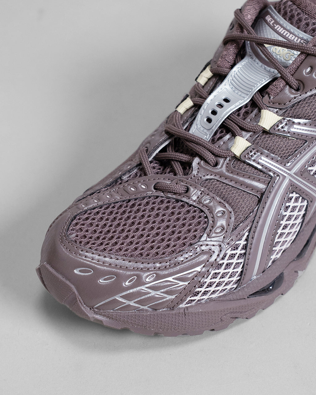 アシックス GEL-NIMBUS 10.1 の近接ショット。ココアパウダー色の甲革とメッシュ、立体構造のダークパープル系アッパーが特徴的なスニーカーの前部アップ