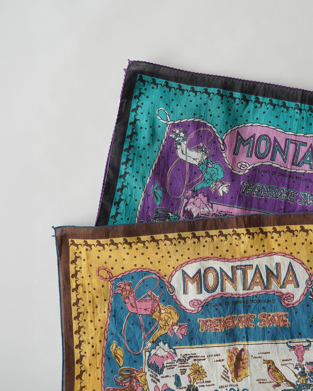 Montana柄のストール2枚を重ねた姿。黒縁と鮮やかなオレンジ・ tealの大胆なプリントデザインが特徴的。