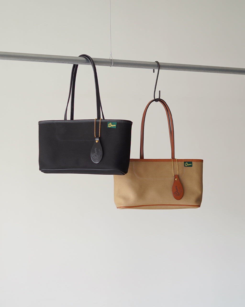 英国ブランドBrady のトートバッグ。黒とベージュの2色展開で、持ち手はショルダー風に掛かり、金具とブランドタグがアクセントになっています。