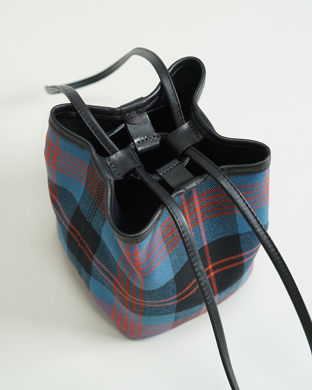 ブレディ KEER LOCHCARRON WOOL CHECKの巾着型ショルダーバッグ。タータンチェック柄のウール生地と黒革パーツの組み合わせが分かる横からの視点。