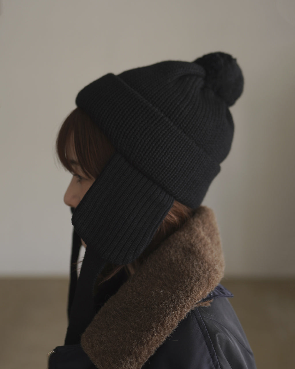 黒い耳付きニット帽の横向き着用で、耳あての長さが見える
