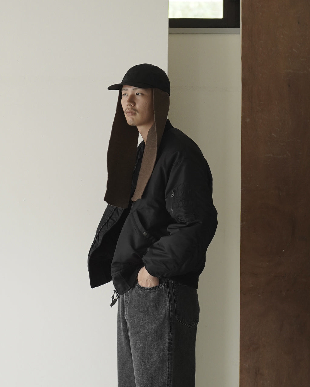 横向きの着用イメージ。黒キャップのつばと、耳まわりまで覆うブラウンのニットが輪郭を作って見える