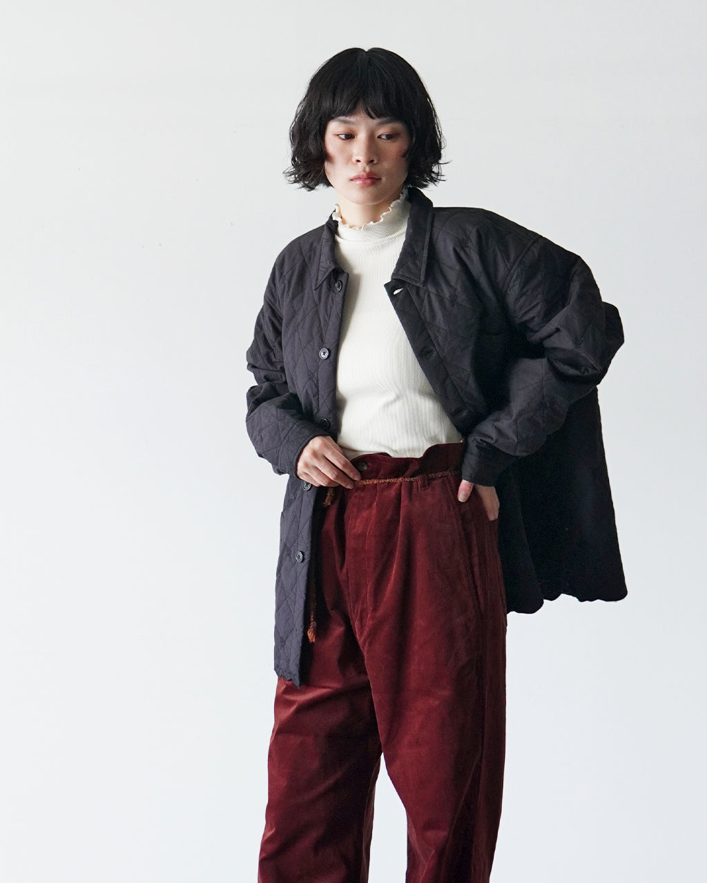 黒系の刺繍スクロップが特徴のジャケットを羽織り、白ニットとボルドー系のパンツを合わせた女性モデルの着用ショット。クラシックなブラック系生地の軽やかなシルエットが際立つ表情