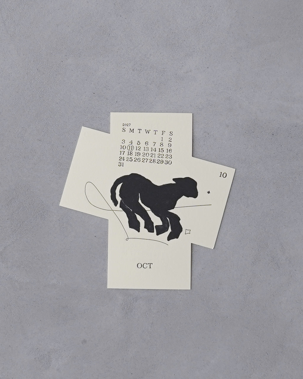 2027年版の Running 干支カレンダー、正面から見える羊のシルエットと月間カレンダーが印刷されたデザイン。紙質の風合いとシンプルな構図が特徴的な一枚。