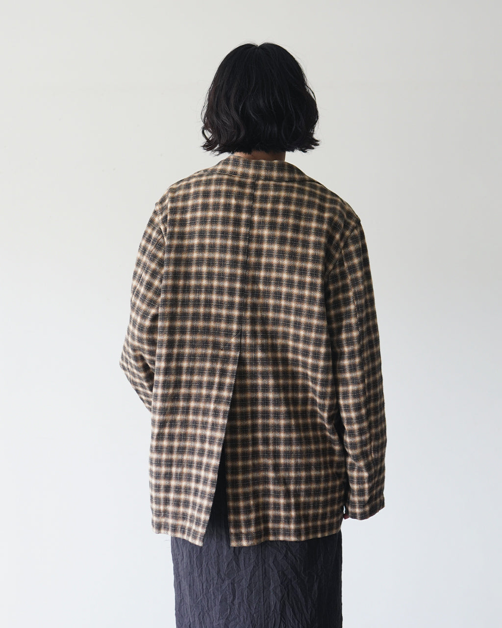 Brown-Checkのジャケットを後ろから見た全体像。ゆったりとしたシルエットにチェック柄の生地と裏地のディテールがわかる背面ショット。
