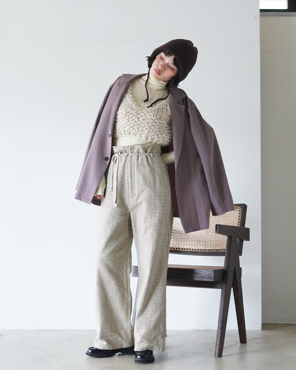モーブカラーの Ease of Mood Jacket を羽織り、チェック柄パンツとニットトップスを合わせた着用イメージ。肩周りのゆとりとラペルの構造的なラインが際立つ写真。