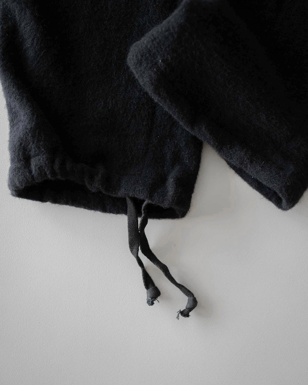 黒系の起毛素材が特徴のパンツの裾近くをアップで捉え、絞り紐と保温性のある表情が見えるディテール写真