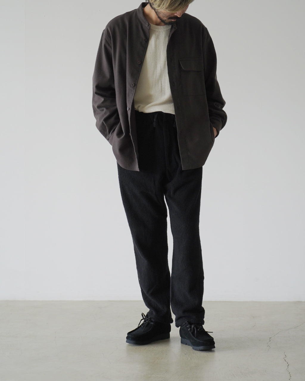 ブラックのSilk Wool Fleece Pantsを着用した男性の全身ショット。ゆったりとしたリラックスシルエットで腰周りにゆとりがあり、裾へ向かって細くなる形状が窺える。