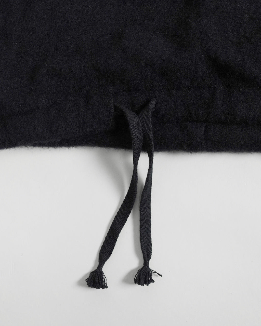 ブラックのSilk Wool Fleece Pullover KS26FCS01の裾付近アップ。裾のドローコードと柔らかな毛足の質感が見て取れるディテールショット。