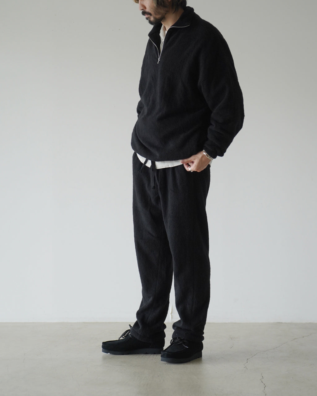 黒の半袖ハイネック風クルーネックではなくスタンドカラーのプルオーバー。左胸元までジップが伸び、リブ袖と裾が絞られたリラックスシルエットの起毛フリース素材のパーカー風ディテール。