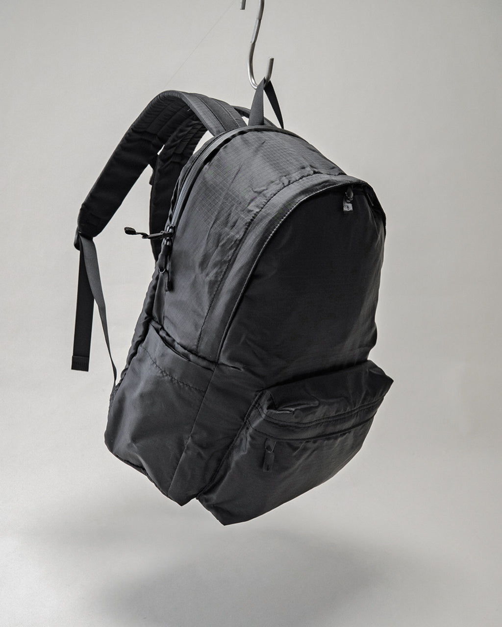 LC by LOWERCASEの Daypack Lite 20Lの前後が見える黒系バックパック。吊り下げ表示で実用的なリュックの形状とポケットが際立つデザイン。
