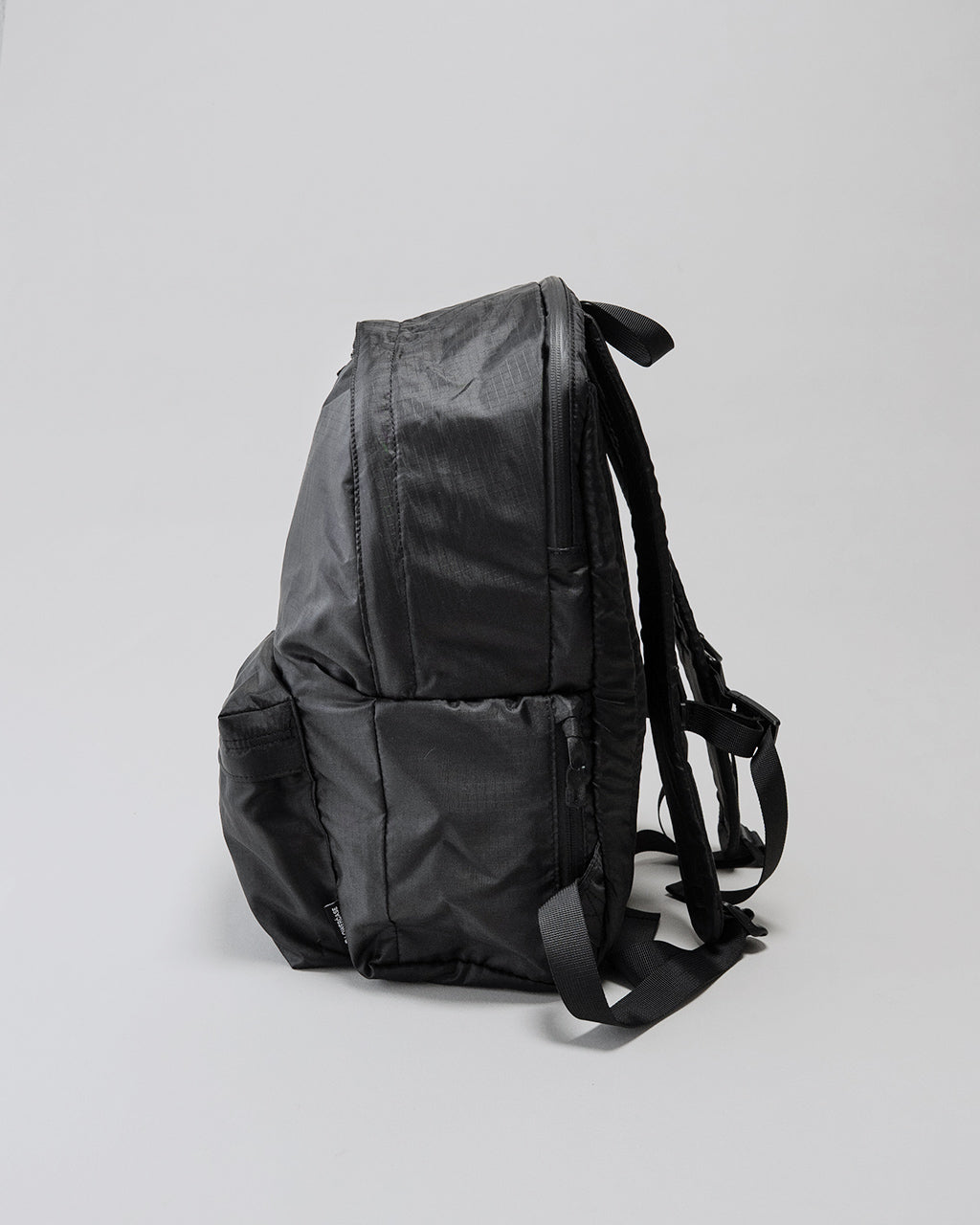 LC by LOWERCASEの20Lリュックサック、黒のバックパック。側面と背面にパッド入りショルダーストラップ、前後にジッパー付きポケットが見える。