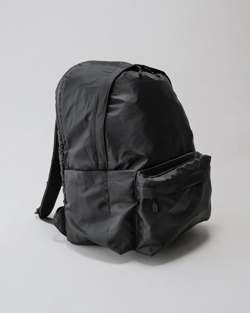 LC by LOWERCASEのDaypack Lite 30L。側面と背面が見えるブラック系のリュックで、メイン収納部と前部ポケットが特徴的。軽量なナイロン生地の質感が伝わる写真。