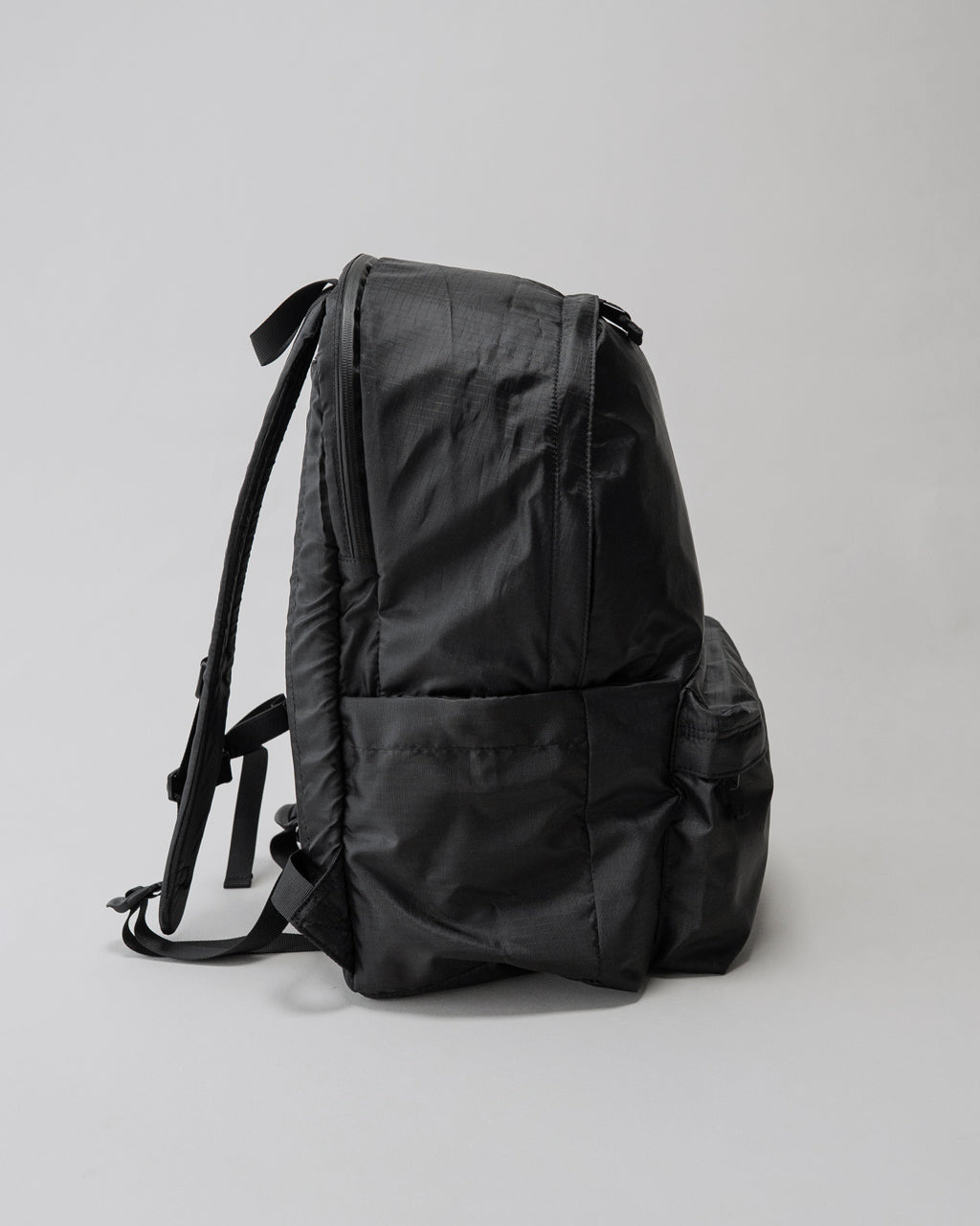 LC by LOWERCASEのバックパック、全体は黒系の素材で背面と側面が見える。容量30L程度のリュックで、サイドポケットとショルダーストラップが確認できる。