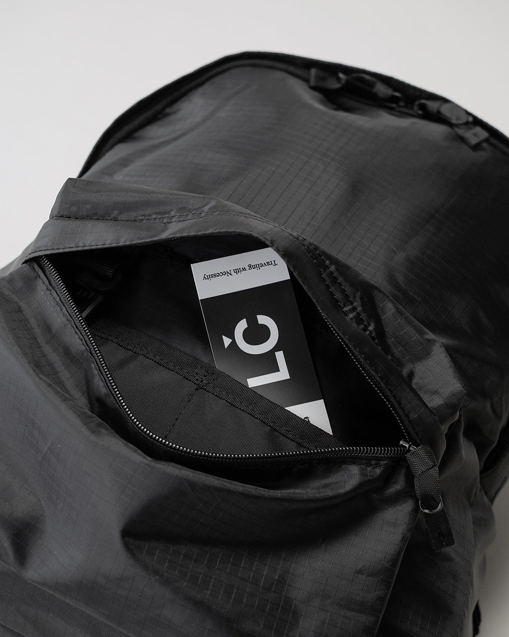 LC by LOWERCASE LC DAYPACK LITE 16Lの背面ファスナーを開いた状態。軽量ナイロン生地とジッパー、内部ラベルが見える約16リットル容量のデイパック。