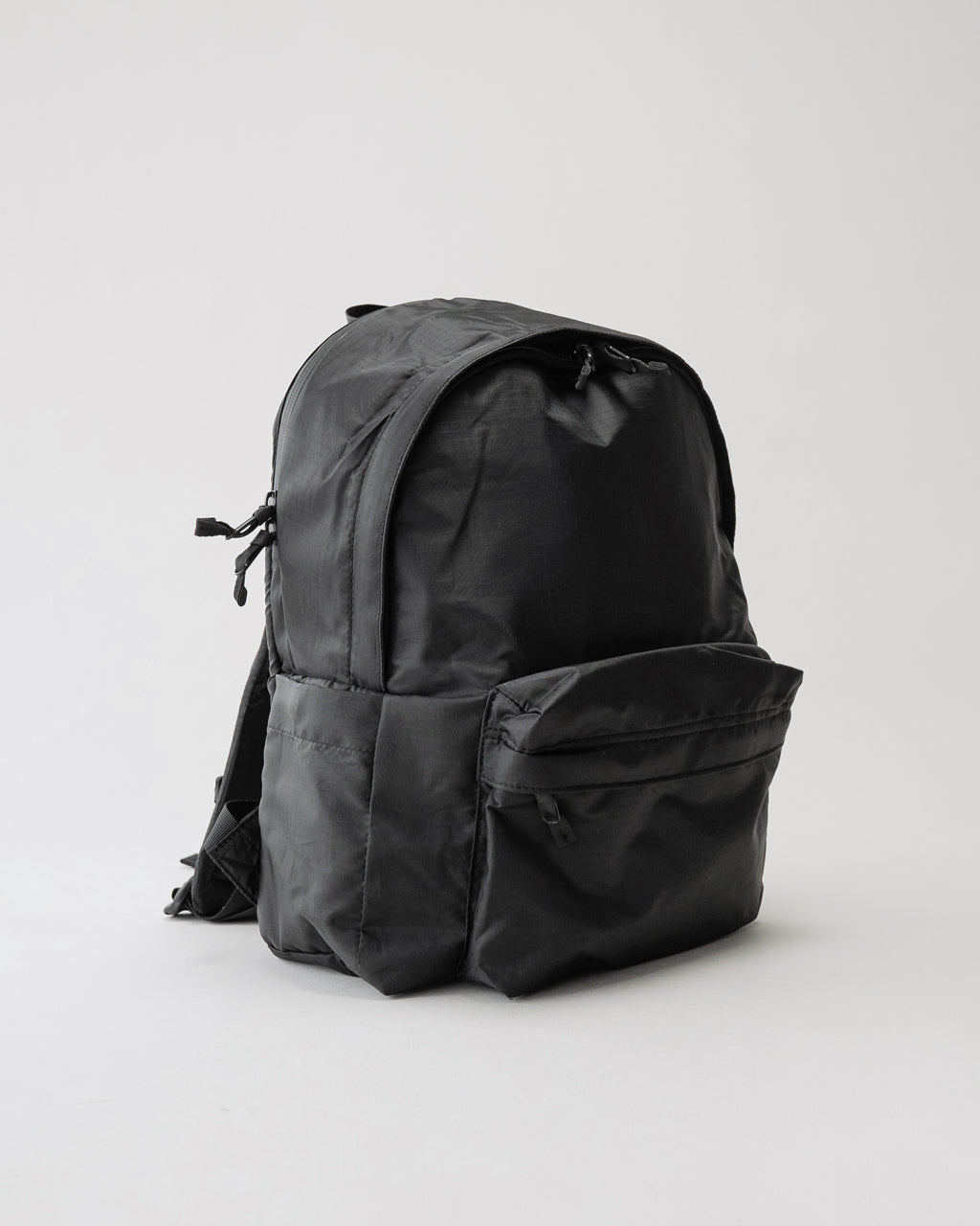LC by LOWERCASEのLC DAYPACK LITE 16Lの黒系バックパック。背面と前ポケットが見え、軽量ナイロン素材の質感が伝わる撮影ショット。