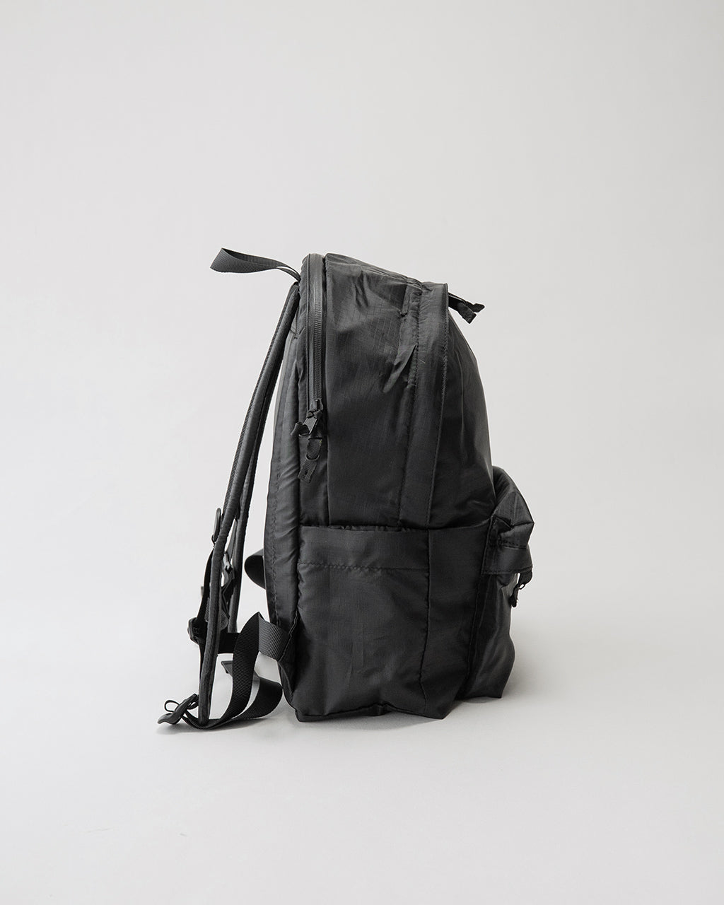 LC by LOWERCASE の DAYPACK LITE 16L、背面とサイドにポケットがある黒のリュックサック。薄手のナイロン生地で縦長のシルエットが特徴。