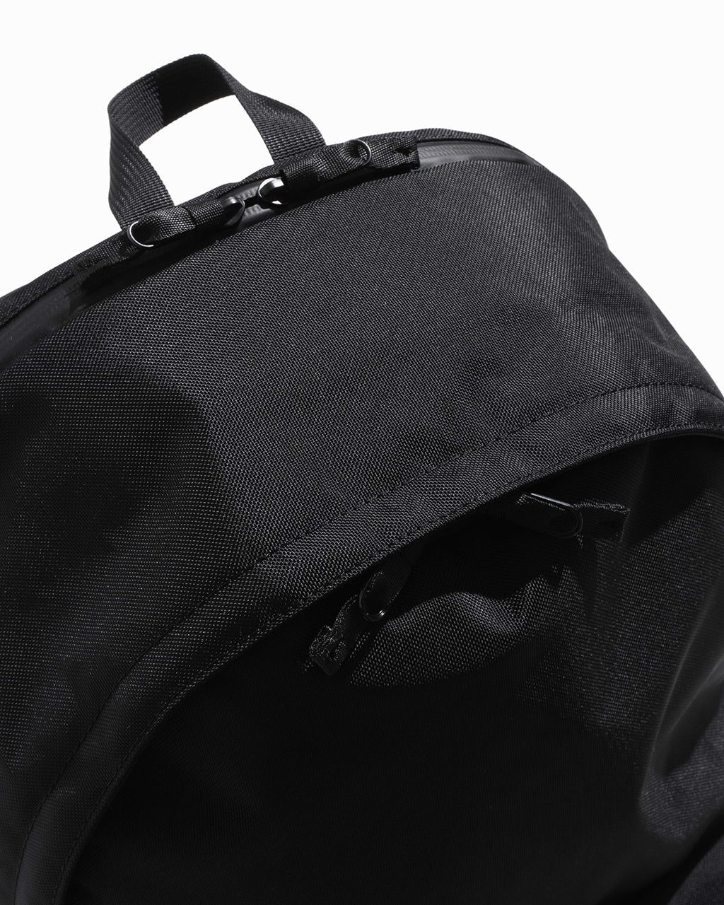 ブラックのDAYPACK Msize。トップのハンドルとジッパー周りの細部が見え、耐久性のある840デニールナイロンの質感が伝わるアップショットです。