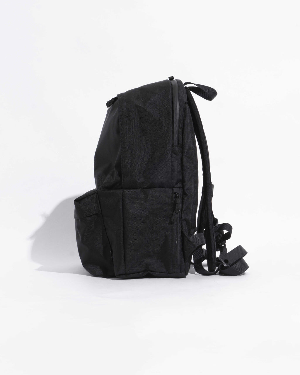 DAYPACK Msizeの側面ショット。黒系のバックパックで側ポケットとショルダーハーネス、背面の形状がわかる画像です