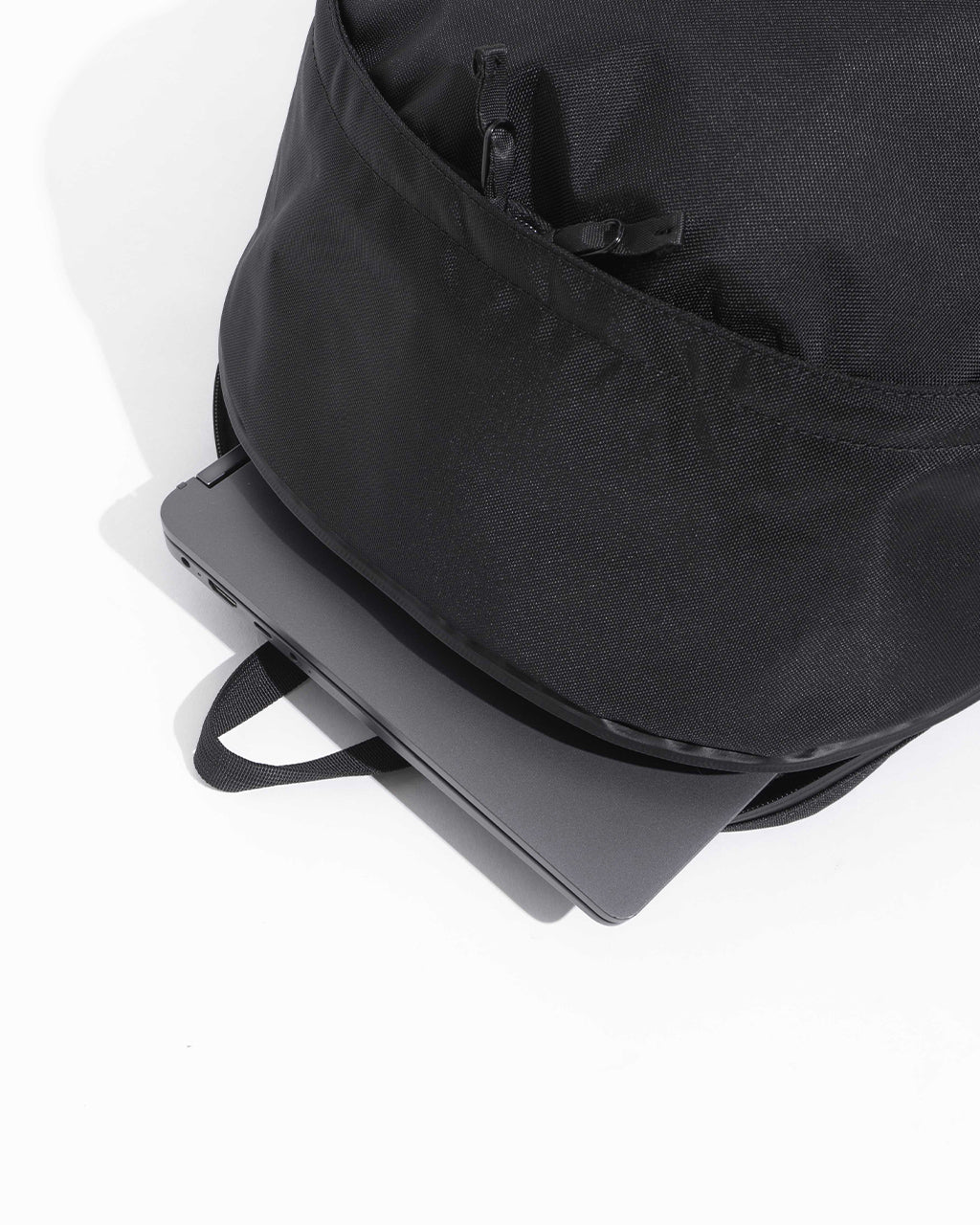 DAYPACK Lサイズの前面と底部を捉えたアップ写真。耐久性のある840デニールナイロンと外部ジッパーのディテールが見えるブラック系バックパック。