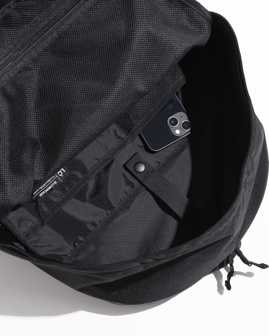 DAYPACK Lsize の内部ポケットとスマートな収納部を見せるブラックのバックパック。PCスリーブやフロント・サイドポケットの詳細が確認できるデザイン。