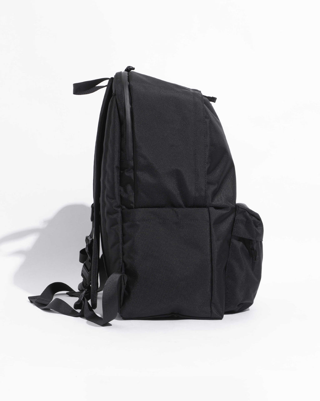 ブラックの DAYPACK Lサイズの側面ショット。背面とサイドポケットが크ーンと見える、シンプルで丈夫そうなデイパック