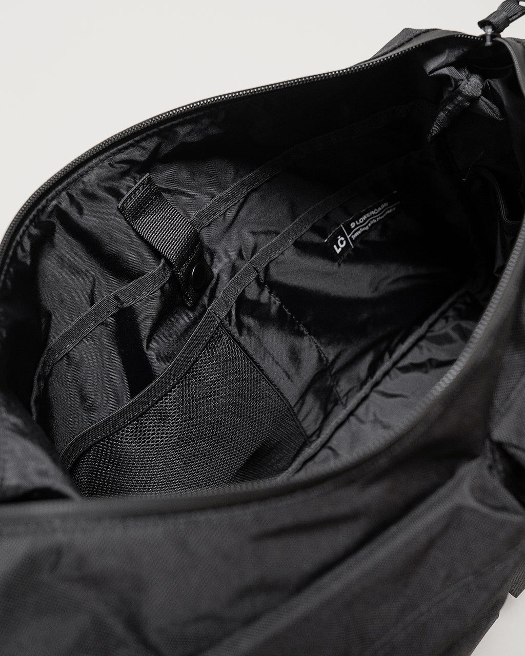 LC by LOWERCASEのショルダーバッグLサイズの内装を上部から見た画像。黒のナイロン生地と内部オーガナイザー、ストラップ留め具が確認できる。