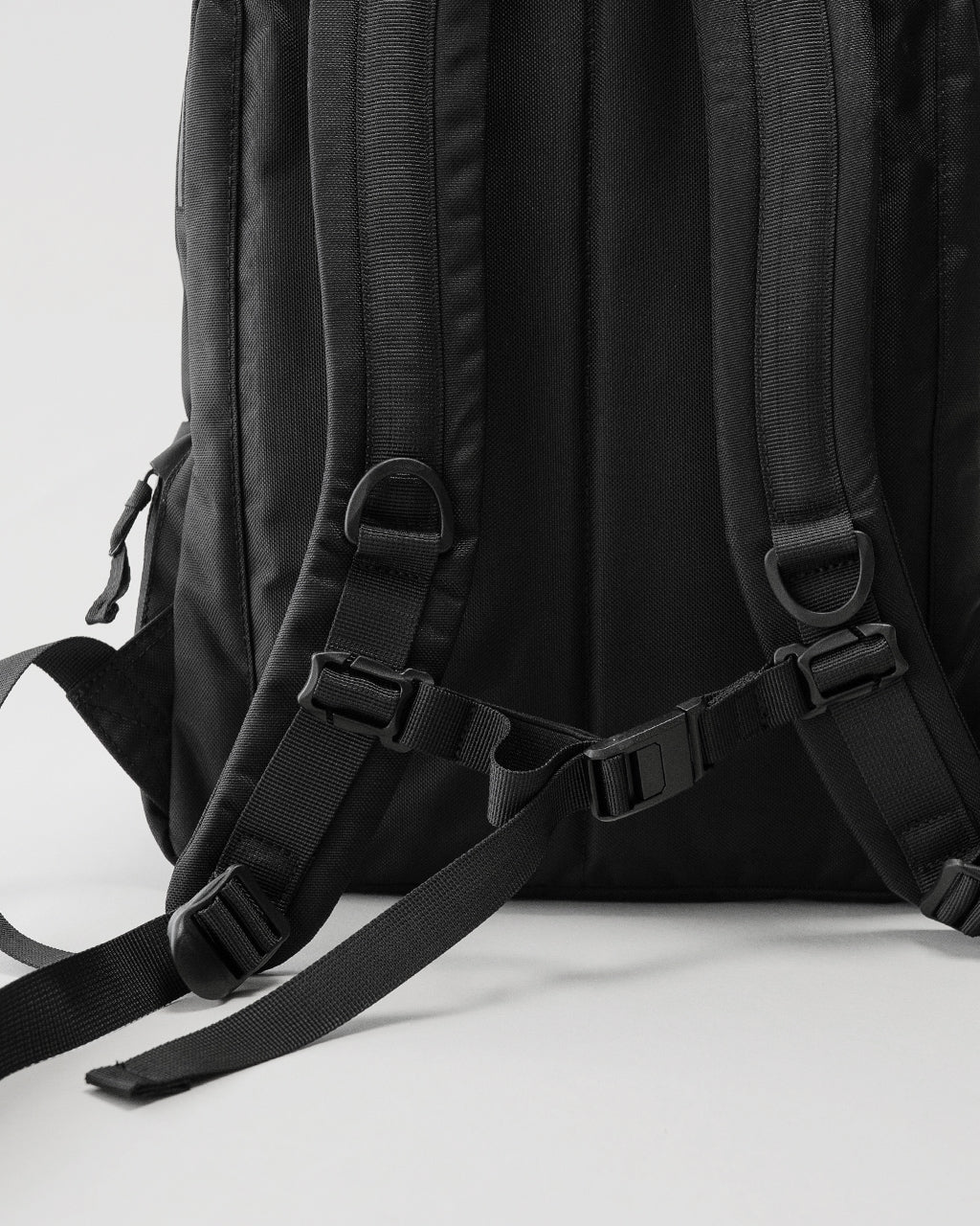 LC by LOWERCASEの Daypack Standard 16L の背面部分。黒いナイロン生地と調節可能な肩紐、ベルトのパーツが見えるディテール画像