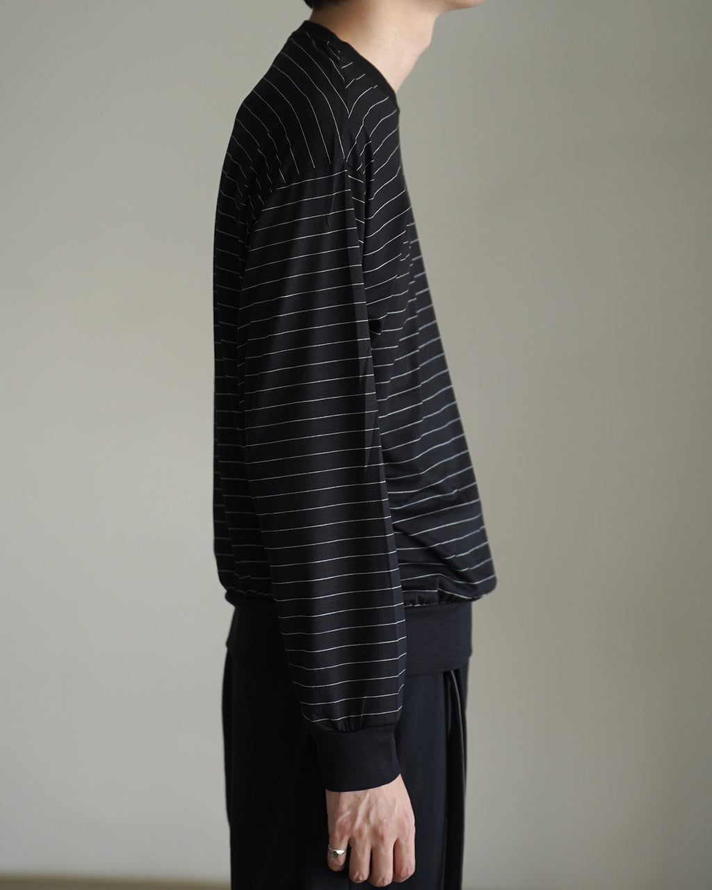 ブラック系ボーダーのクルーネック長袖Tシャツ。袖口と裾のリブがしっかりと締まり、横から見てもラインが綺麗に流れるワイドシルエットのドロップショルダー風デザイン。