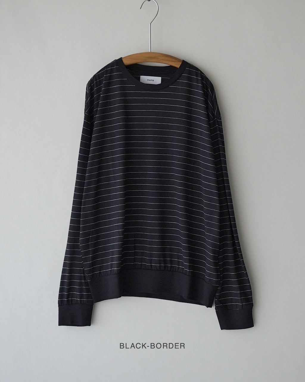 ブラックボーダー柄のクルーネック長袖Tシャツがハンガーに掛かっている様子。首元リブと裾リブが太く、横ストライプが際立つしっかりとした素材感が伝わる一枚。