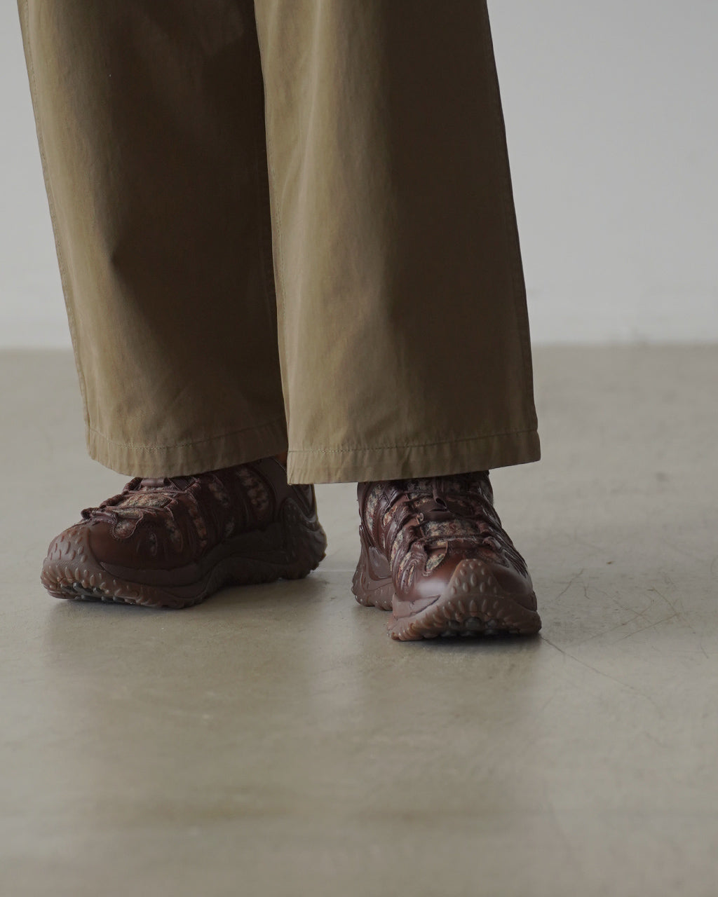 ダークウォルナットカラーのハリスツイードとレザーを使ったMerrellのアウトドアシューズ、裾まで見える丈のパンツと組み合わせた着用スタイルの横姿。
