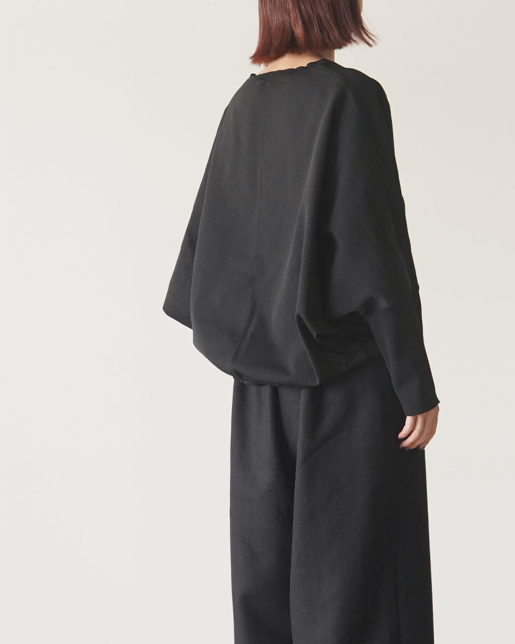 mizuiro indの cocoon P/O を着用し、背中が見えるアングルでドロップショルダーとゆったりしたシルエットを強調したブラックのプルオーバー画像