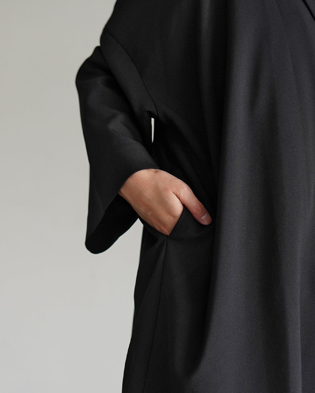 mizuiro indのwide tailored shirt JKのブラック系素材を着用した袖口の三つ折りデザインとポケットをアップで捉えた正面寄りの一枚。落ち感のある生地とシルエットが映える近接ショット