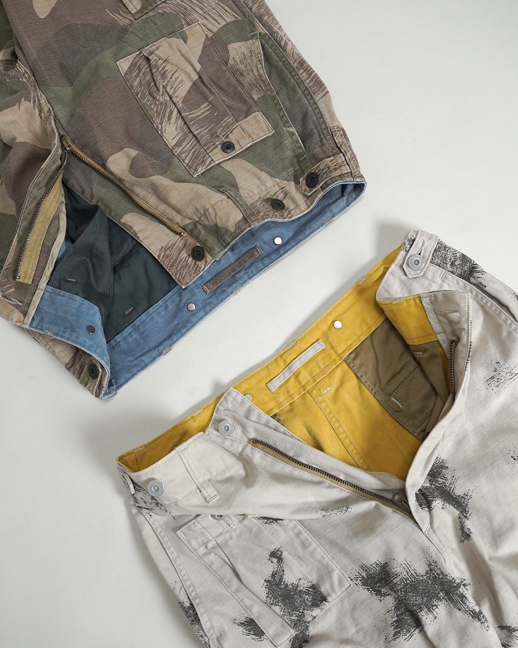 フェードカモのARMY CARGO PANTの前後切替カラーとカーゴポケットが特徴的なパンツ。迷彩柄の生地と裏面の色味が分かる横向きショット。