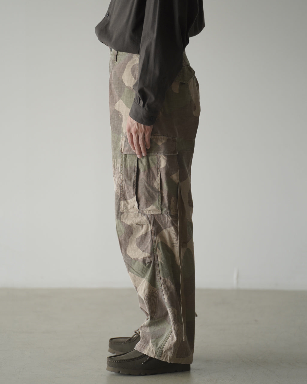 ARMY CARGO PANT FADE CAMOの側面ショット。カモフラージュ柄のパンツで、側ポケットとカーゴポケットのディテールが見える着用前提のパンツ姿勢を捉えています。