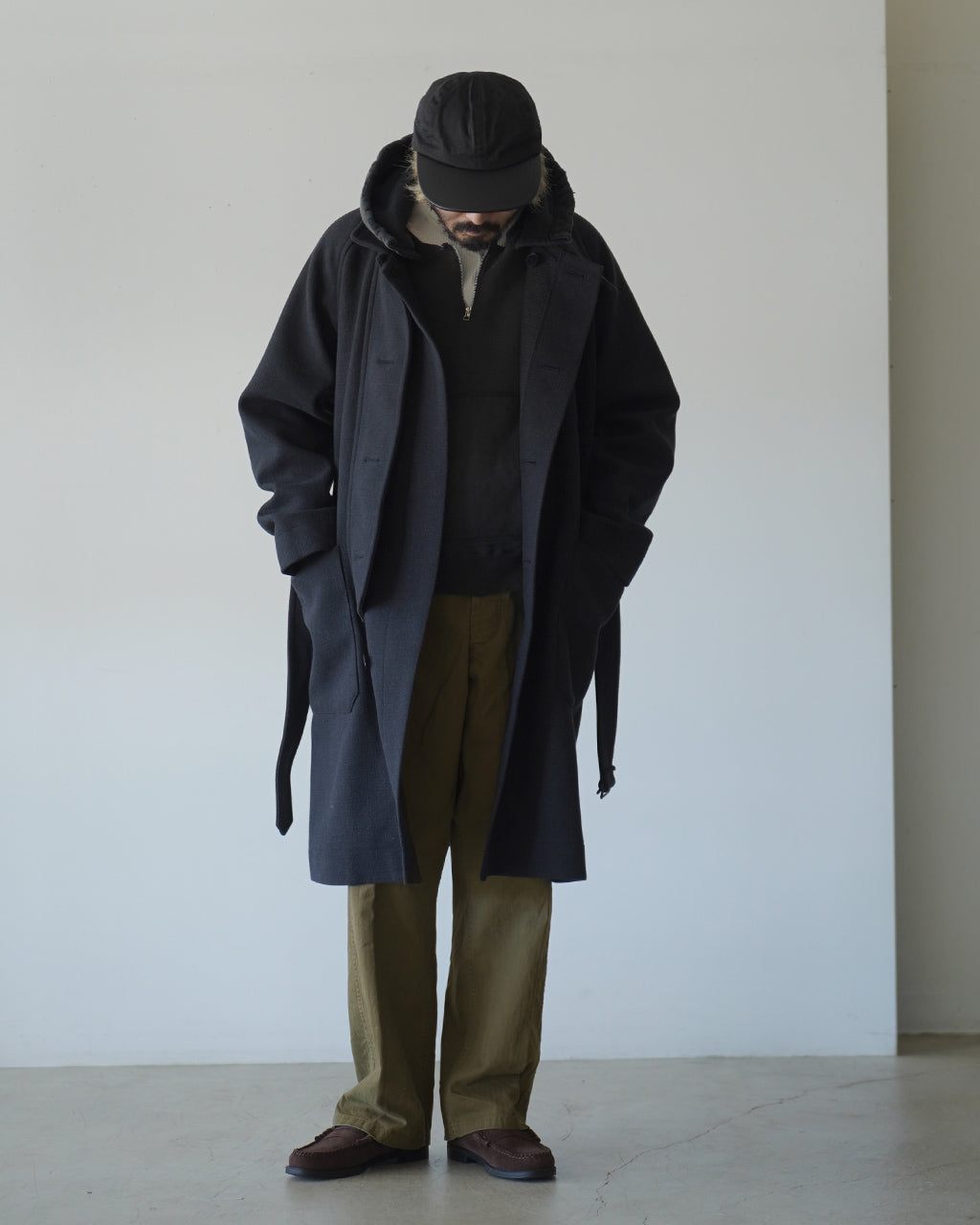 黒系のコートを着用した男性が反対を向かず前方を見下ろす姿。大きめのカーゴポケットが特徴的なU.S ARMY 2 POCKET CARGOを着用したスタイル画像