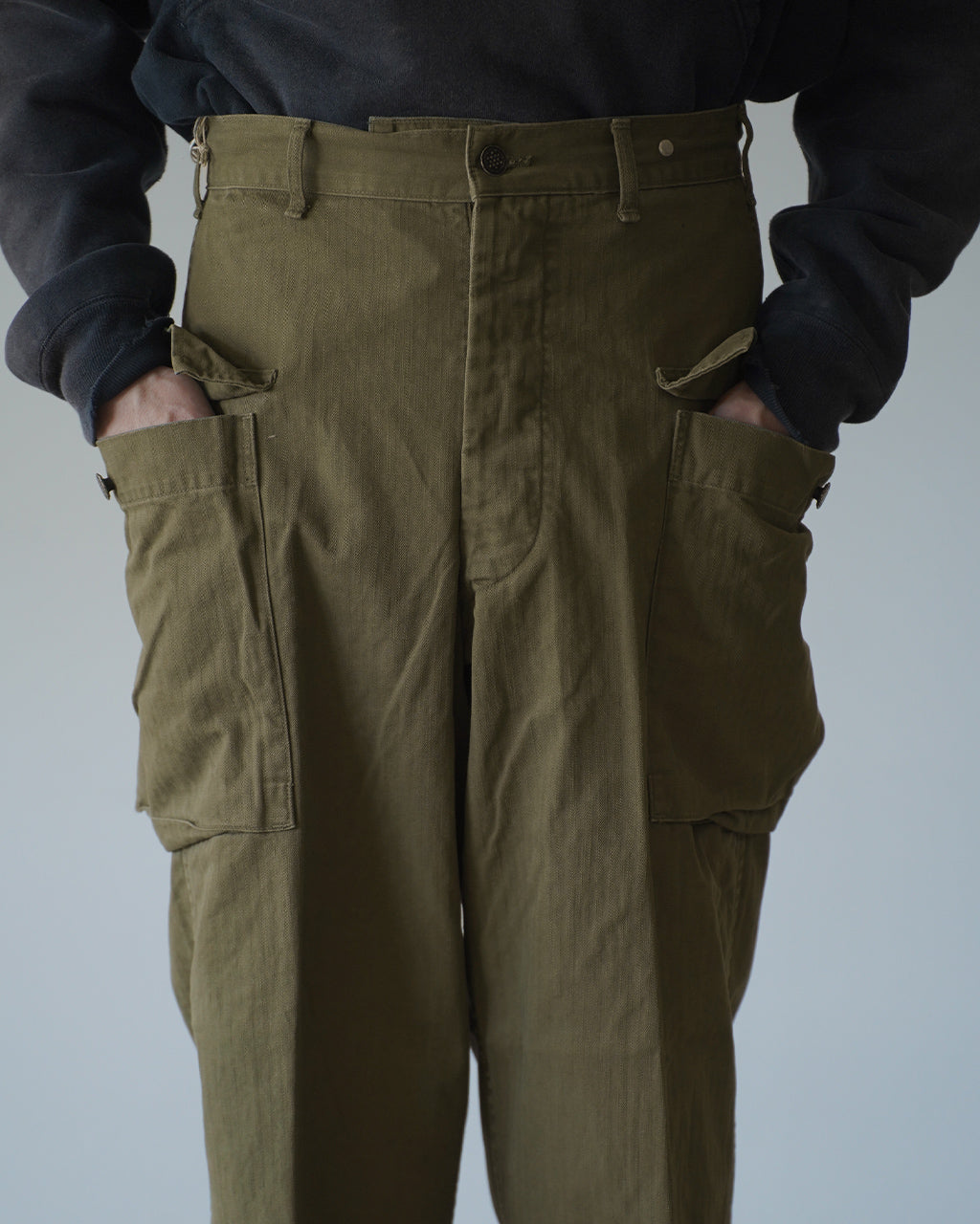 カーキのU.S ARMY 2 POCKET CARGOパンツを前身頃からアップで捉えたショット。フロントボタンとコインポケットが見え、腰周りのベルトループと丈感が特徴的。