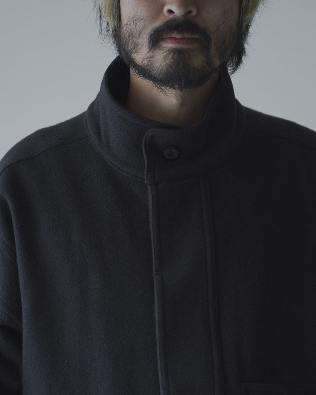 チャコール系のVESTE ABOSのアップ。高めのスタンドカラーと比翼フロントのデザインが特徴的なウールジャケット前身頃の接近ショット。