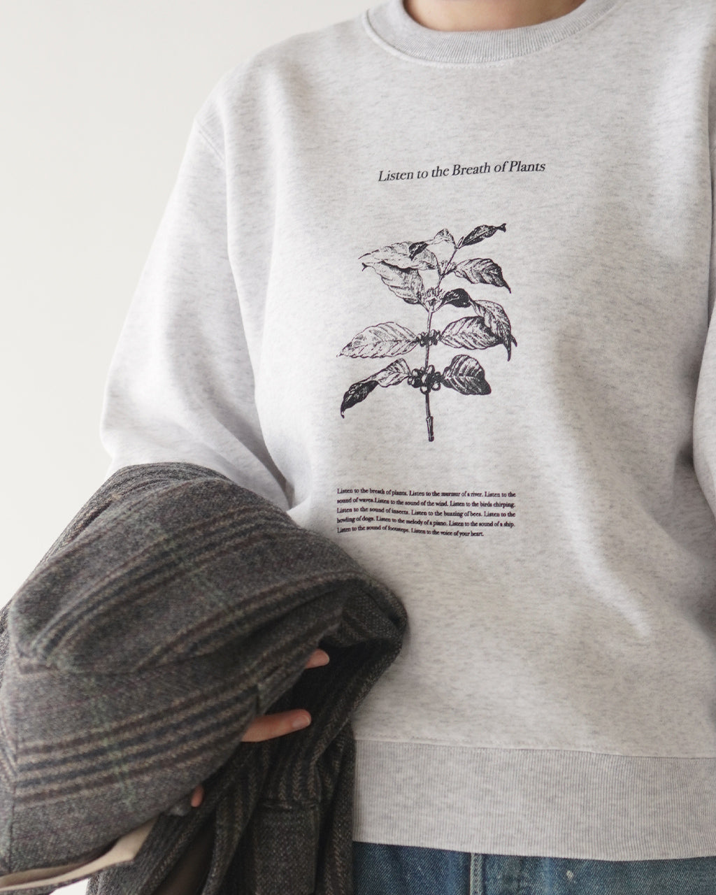 POET MEETS DUBWISEのBREATH OF PLANTS SWEATの胸元プリントのアップ画像。白系のスウェットに植物の線画が淡く映える印象のディテールショット。