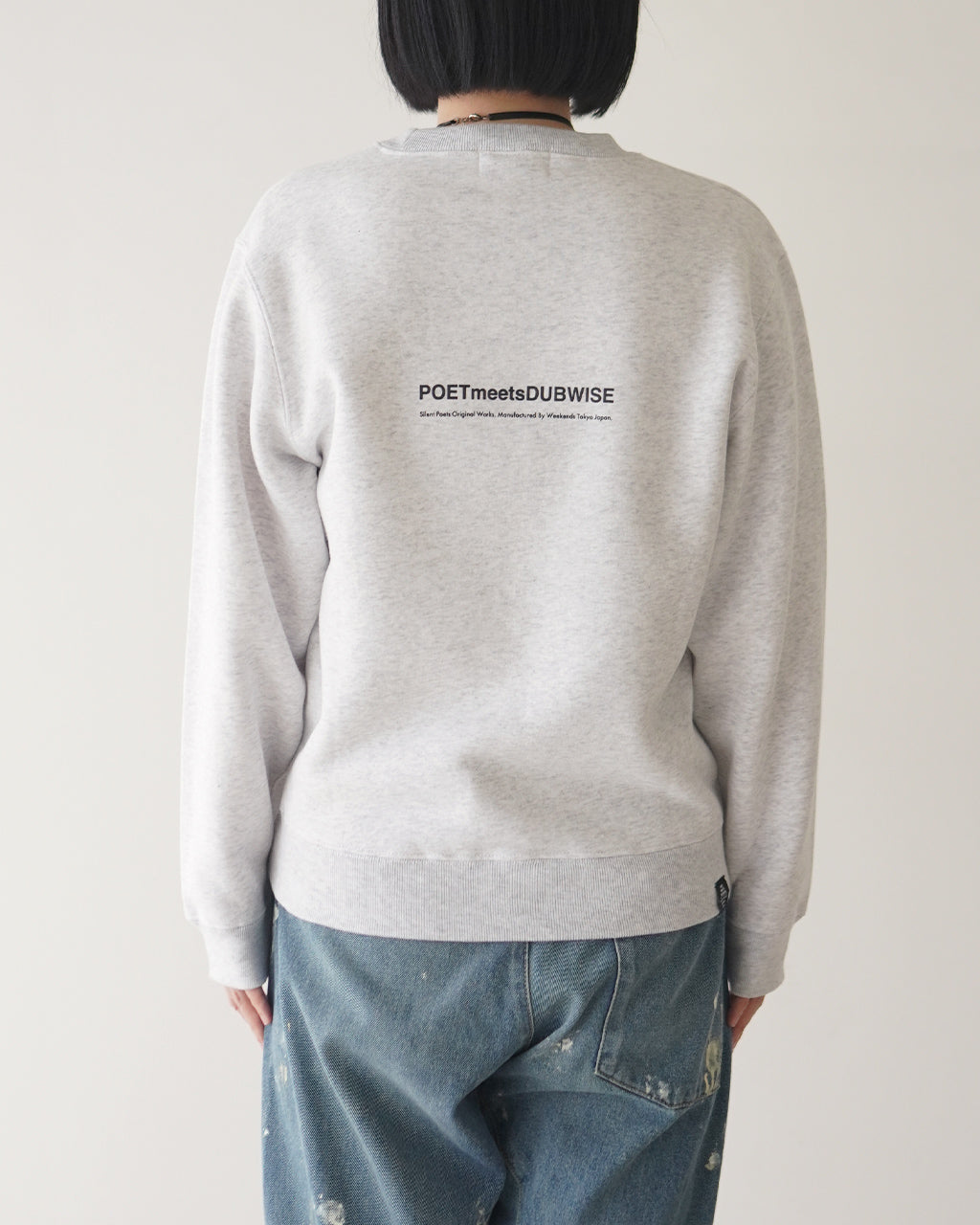 背面にブランド名POETMeetsDUBWISEのロゴがプリントされたグレーのスウェット。ややゆとりのあるシルエットで肩周りが広く、丈は腰周りまでの長さです