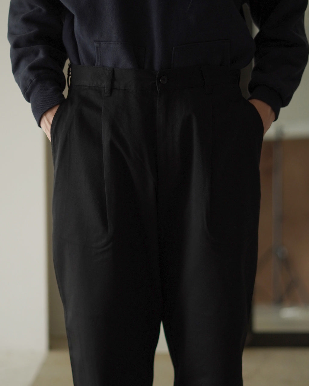 腰周りに適度なゆとりがあり、裾に向かって細くなる黒系パンツの上半身とウエスト周りアップショット。