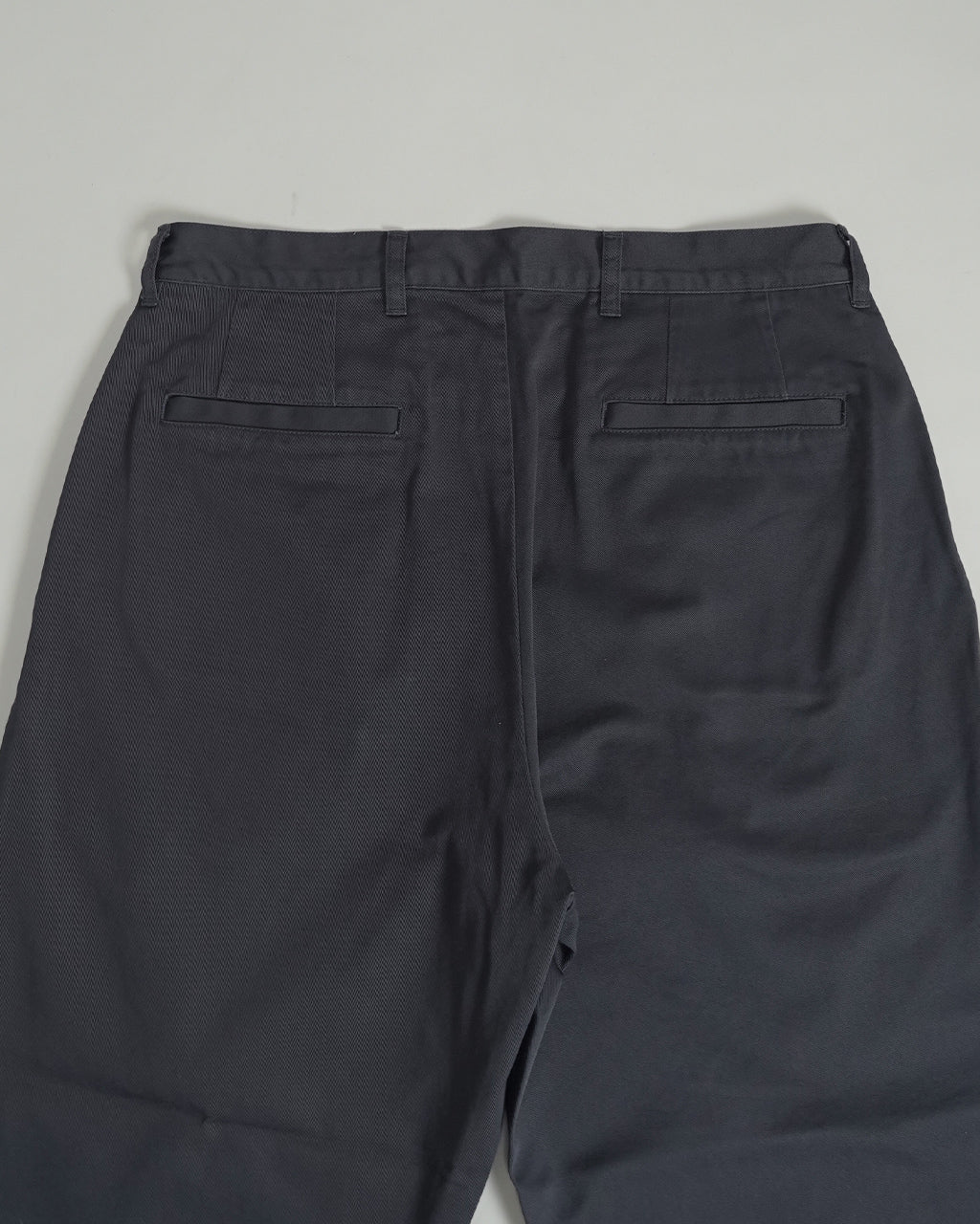 ポータークラシックの Duke Ellington Chinos の背面アップ。深いネイビー系のカラーで、ウエスト周りのタックと裾にかけてのすっきりとしたシルエットが窺える。背面ポケットをのぞくデザインが分かるダークカラーのパンツ写真