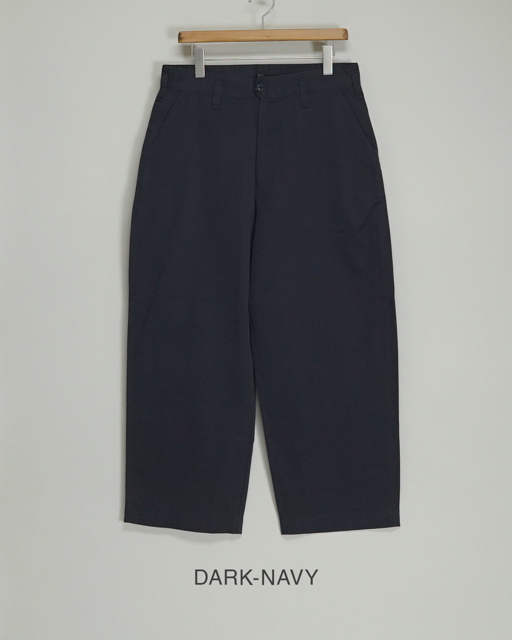 PORTER CLASSICのGene Kelly Chinos、ダークネイビーのパンツをハンガーで展示している前面ショット。ウエスト周りのベルトループ・ポケットの形状が確認でき、裾までゆとりのあるワイド気味のシルエットが分かる画像です