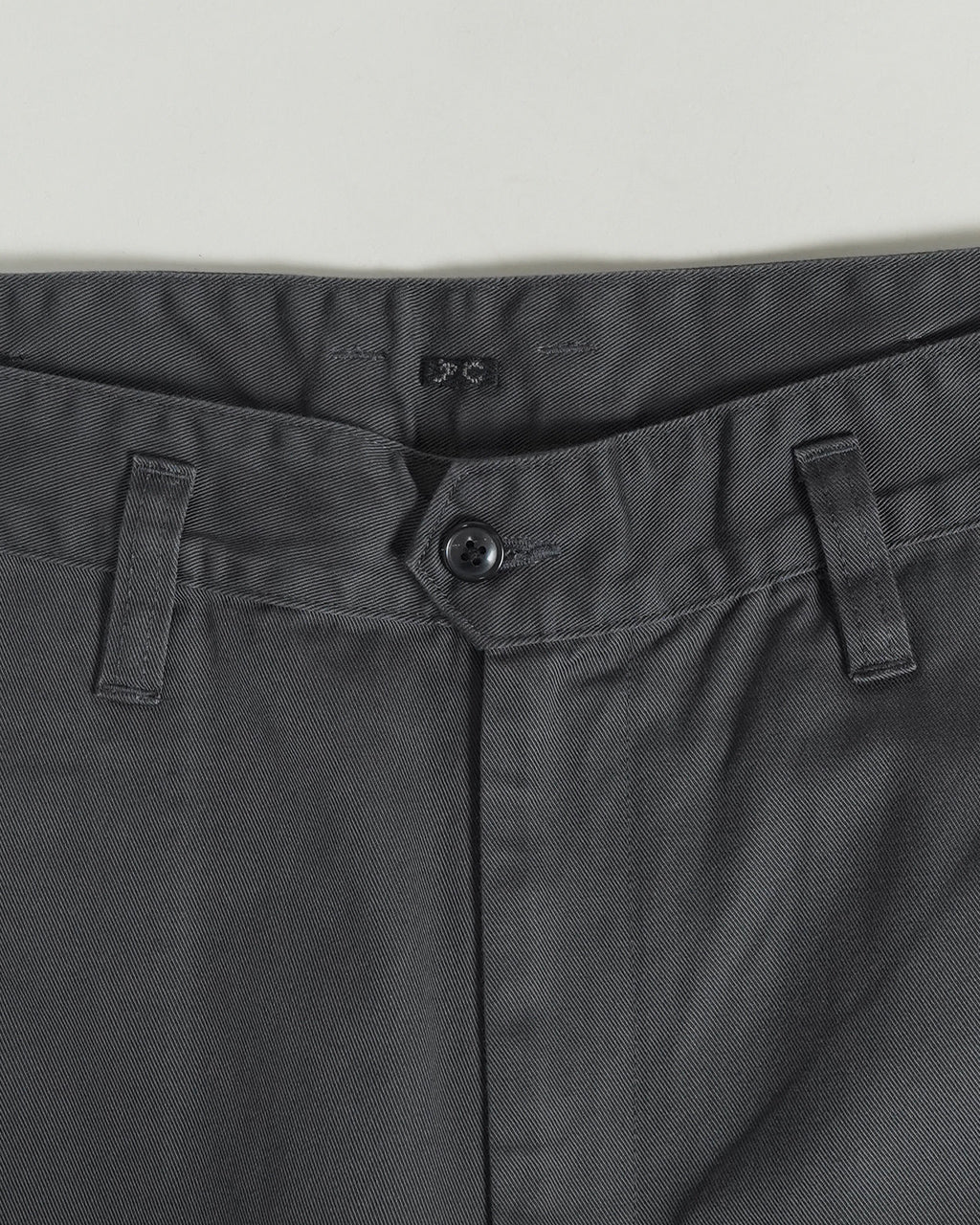濃灰色系のポリテックス感がある PORTER CLASSIC の GENЕ KELLY CHINOS のウエスト周りと前立て部分。ベルトループとボタン留めが見えるアップショット。