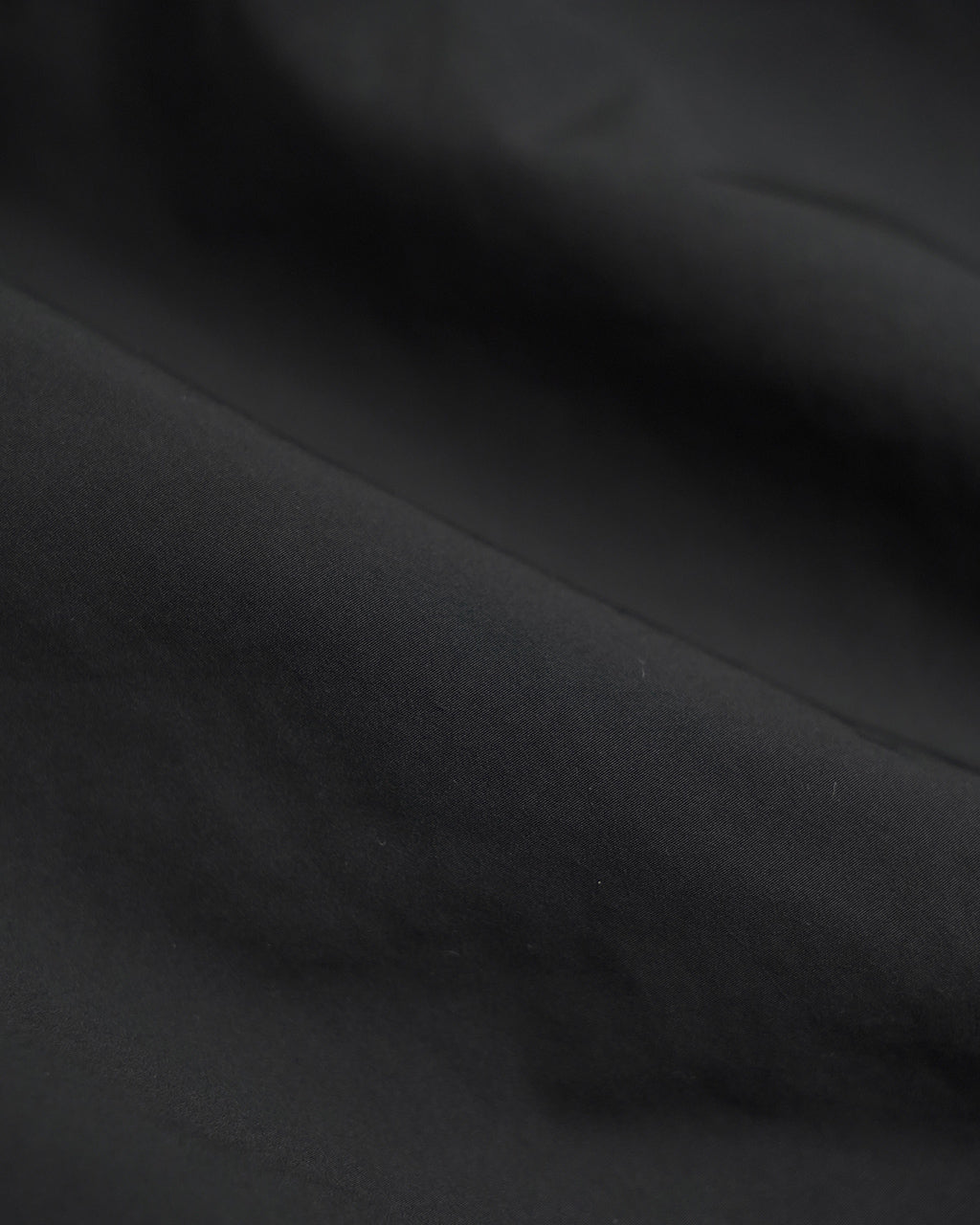 黒系の滑らかな生地アップ。光の当たり具合で質感が分かる、PORTER CLASSICのWeather Coach Jacketの内側生地近接ショット