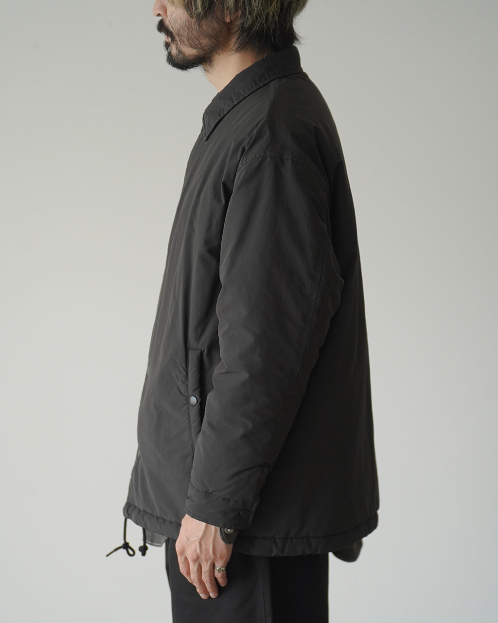 PORTER CLASSIC WEATHER COACH JACKETの横からのシルエット写真。黒系のコーチジャケットで、すっきりとした丈感と袖幅を確認できる。